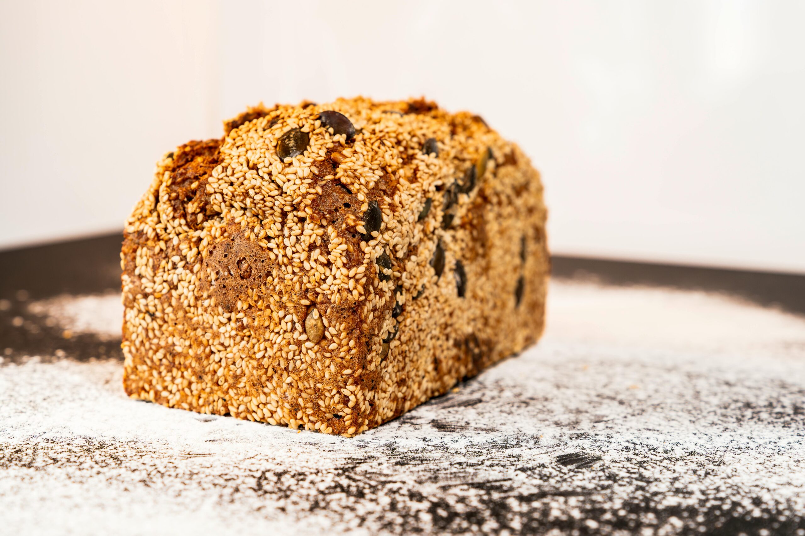 Close-up of artisanal sesame bread on a floured surface, showcasing texture.