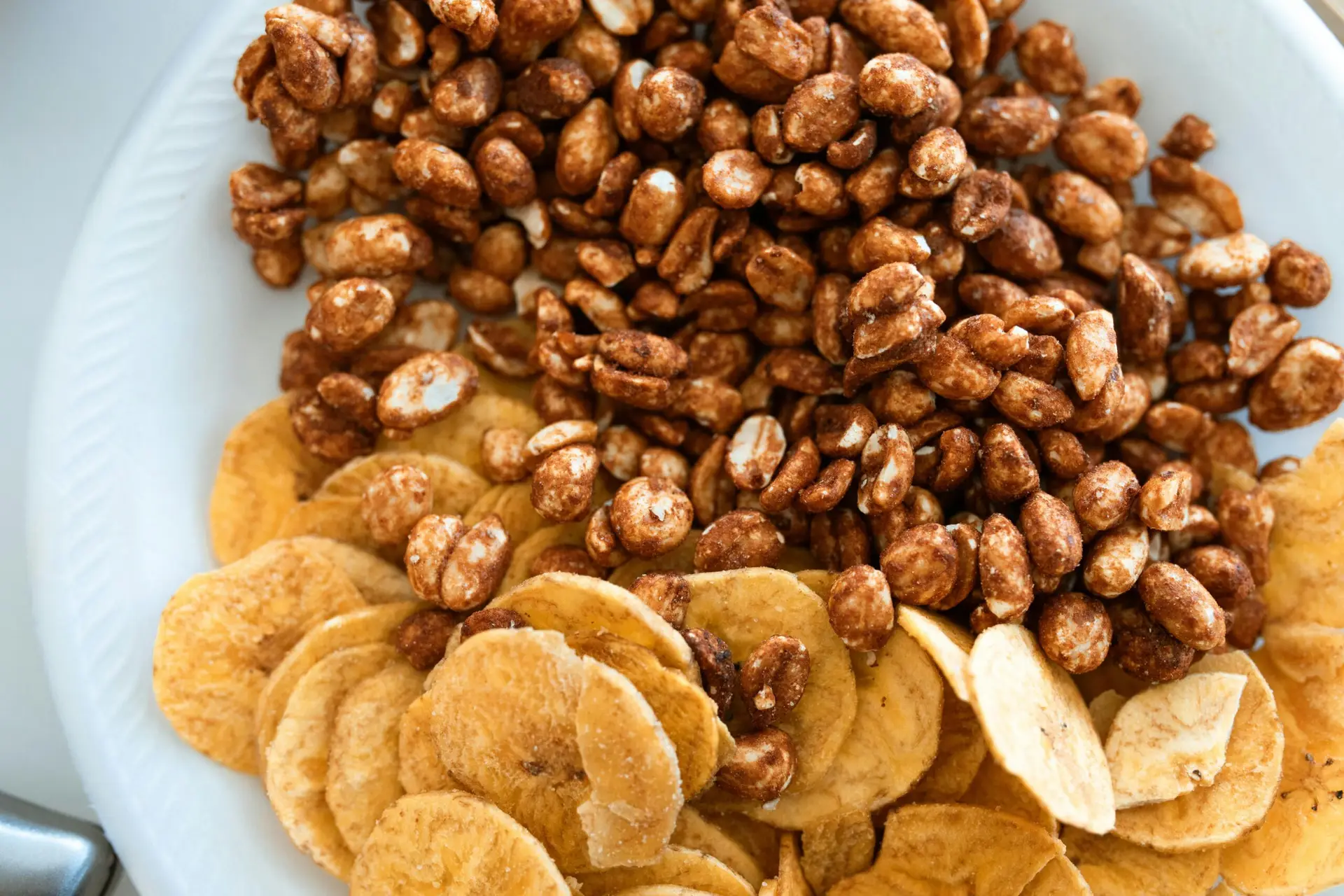 Sch&uuml;ssel mit ger&ouml;steten Erdn&uuml;ssen und Bananenchips